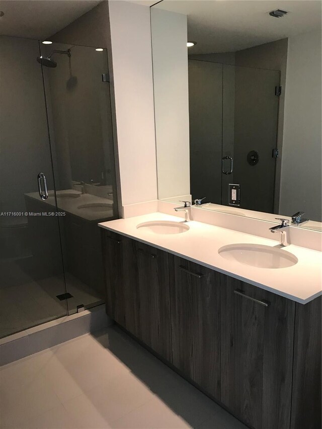 bathroom featuring a shower with door and vanity