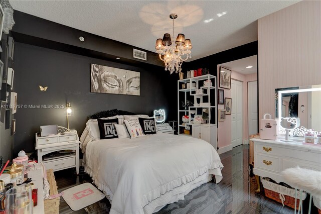 bedroom with dark hardwood / wood-style flooring, a textured ceiling, and an inviting chandelier