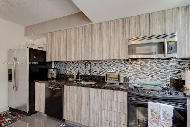 kitchen with backsplash, black appliances, sink, dark stone countertops, and light brown cabinetry