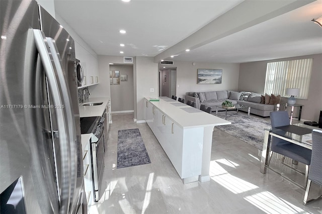 kitchen featuring white cabinets, a kitchen island, sink, stacked washer / drying machine, and stainless steel fridge