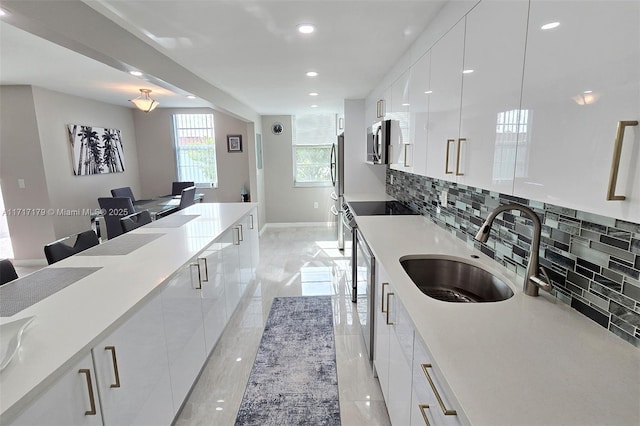 kitchen with white cabinets, appliances with stainless steel finishes, decorative backsplash, a kitchen breakfast bar, and sink