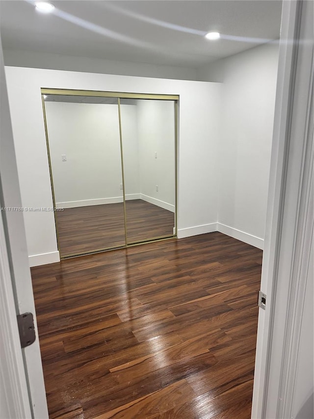 unfurnished bedroom with a closet and dark wood-type flooring