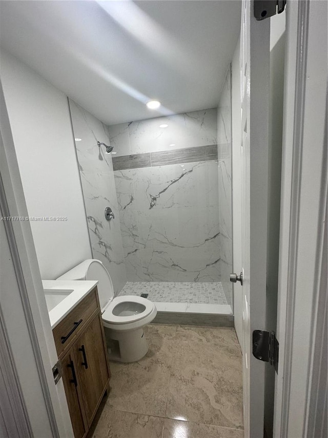 bathroom featuring toilet, a tile shower, and vanity