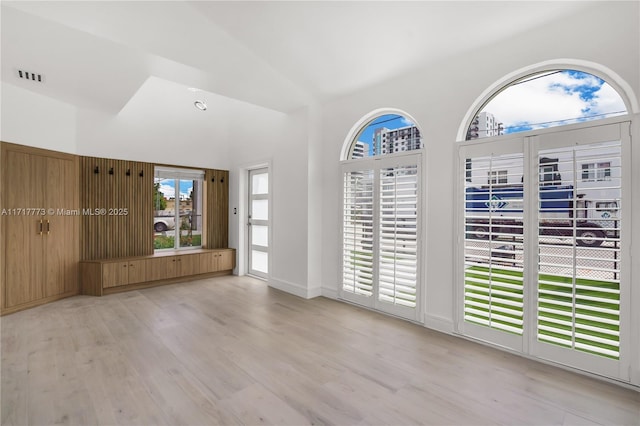 empty room featuring light hardwood / wood-style floors and high vaulted ceiling