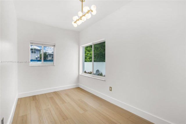 unfurnished room with hardwood / wood-style flooring and a notable chandelier