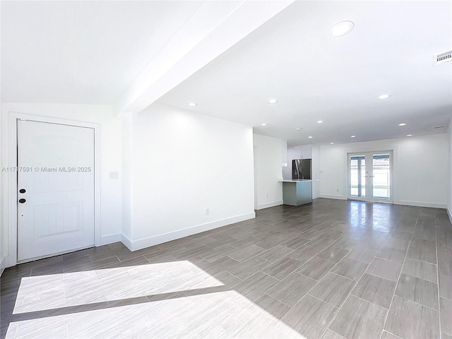 unfurnished living room featuring french doors and lofted ceiling with beams