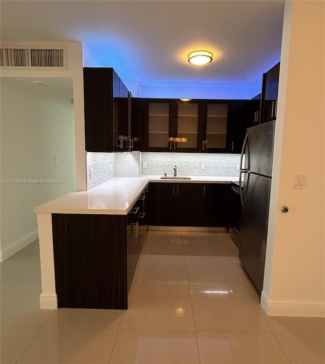 kitchen featuring stainless steel fridge, kitchen peninsula, backsplash, and light tile patterned floors