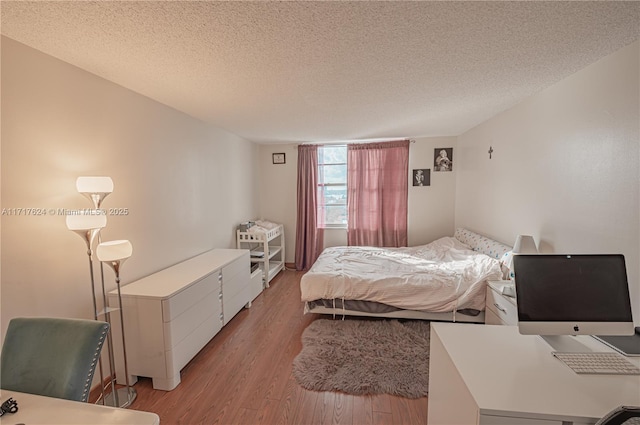 bedroom with light wood-type flooring and a textured ceiling