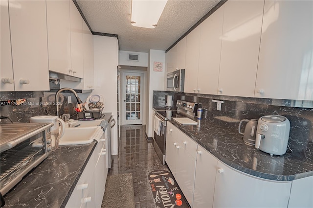 kitchen with tasteful backsplash, white cabinets, a textured ceiling, and appliances with stainless steel finishes