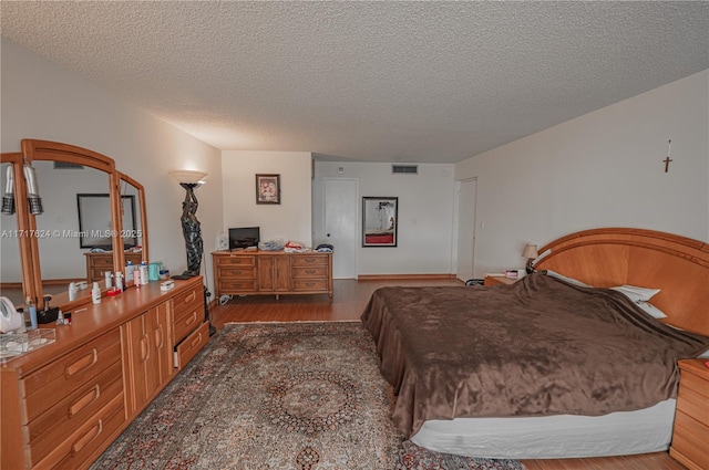 bedroom with dark hardwood / wood-style floors and a textured ceiling