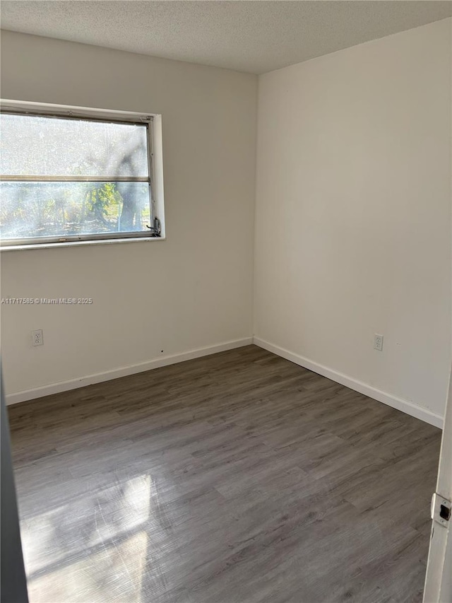 spare room with dark hardwood / wood-style flooring and a textured ceiling