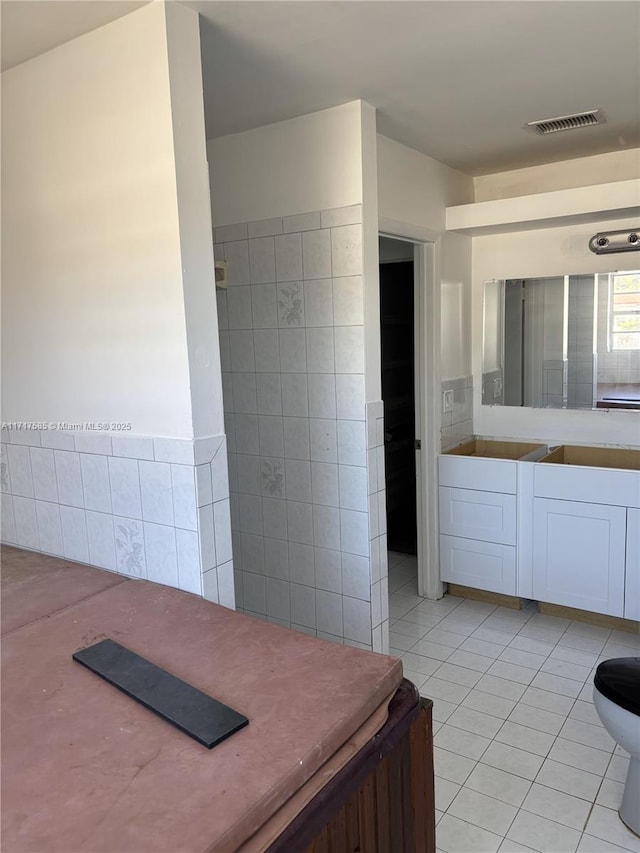 bathroom with tile patterned flooring, vanity, and tile walls