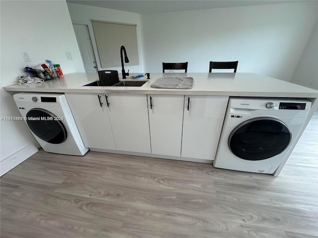 washroom with cabinets, washer / dryer, light hardwood / wood-style flooring, and sink