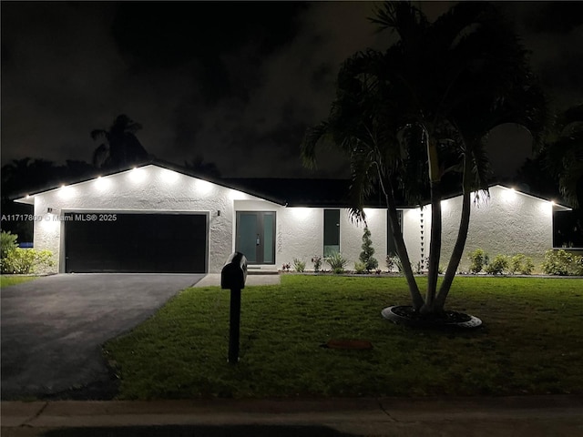 ranch-style home featuring driveway, stucco siding, and a lawn