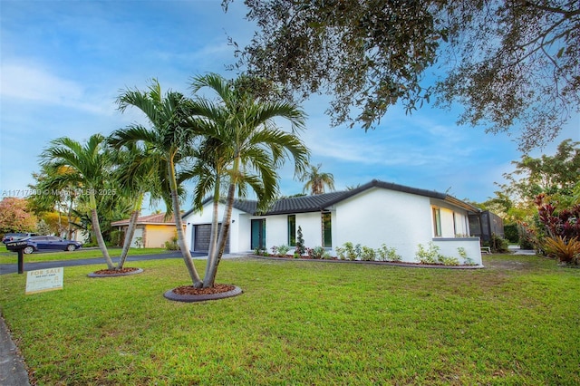 view of front facade featuring driveway, stucco siding, and a front lawn