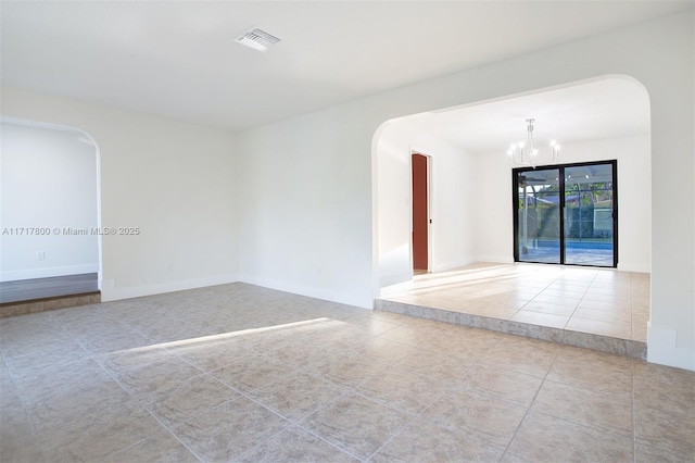 tiled spare room featuring a chandelier, arched walkways, baseboards, and visible vents