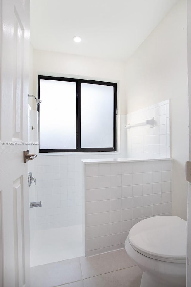 bathroom with a tile shower, tile walls, tile patterned flooring, and toilet