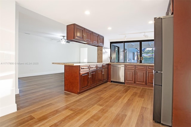 kitchen featuring stainless steel appliances, a peninsula, light wood-type flooring, and ceiling fan
