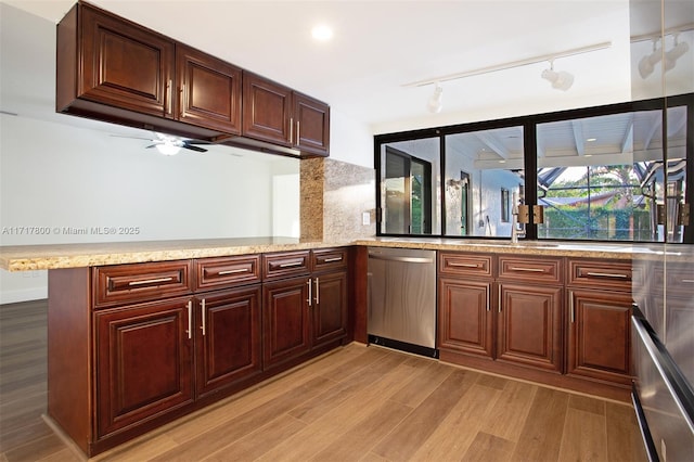 kitchen with light wood-style floors, a peninsula, light stone counters, dishwasher, and a sink