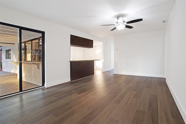spare room with dark wood finished floors, visible vents, baseboards, and ceiling fan