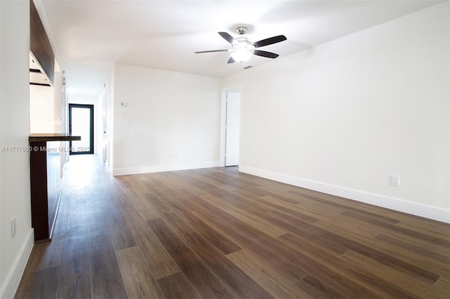 spare room with dark wood-style flooring, baseboards, and a ceiling fan