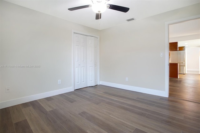 unfurnished bedroom with built in refrigerator, baseboards, visible vents, and dark wood-style flooring