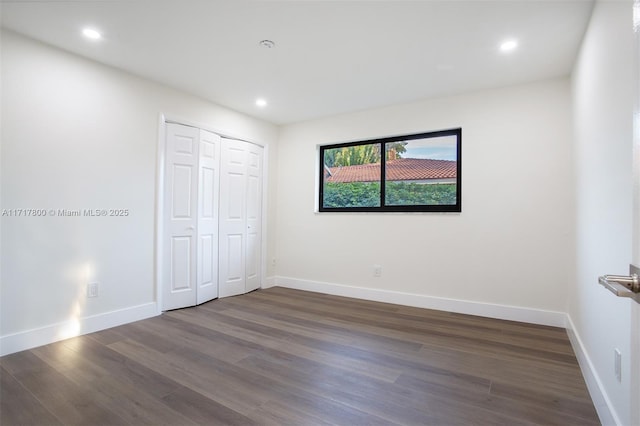 unfurnished bedroom with dark wood-type flooring, a closet, baseboards, and recessed lighting