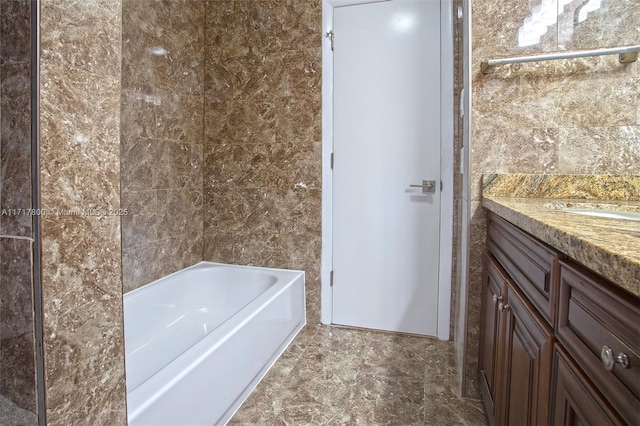 full bath featuring tile walls, vanity, and a washtub
