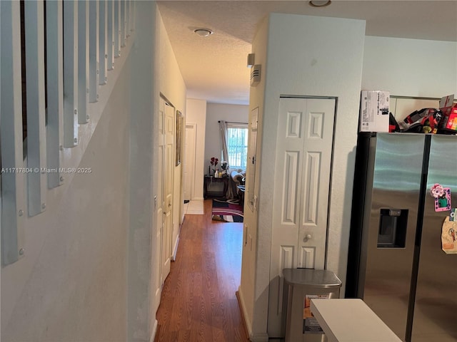 hallway with a textured ceiling and dark hardwood / wood-style floors