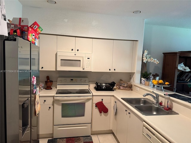 kitchen with white cabinets, light tile patterned flooring, white appliances, and sink