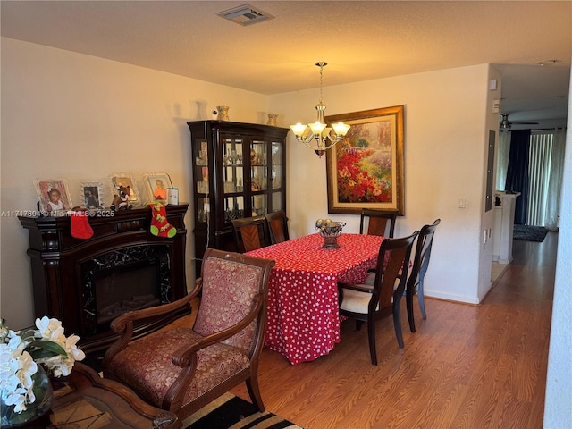 dining room with a premium fireplace, wood-type flooring, and an inviting chandelier