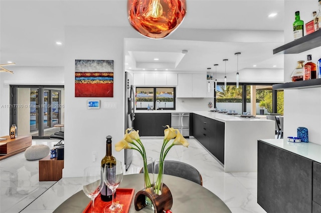 kitchen with a raised ceiling, sink, white cabinets, and pendant lighting