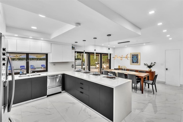 kitchen featuring stainless steel appliances, kitchen peninsula, white cabinets, and hanging light fixtures