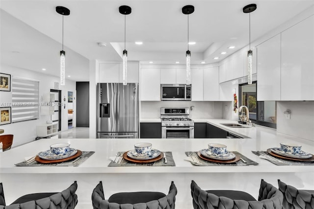 kitchen featuring white cabinetry, sink, hanging light fixtures, kitchen peninsula, and appliances with stainless steel finishes