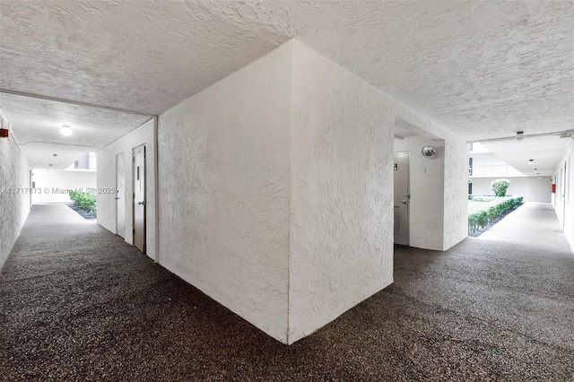 hall with carpet flooring and a textured ceiling