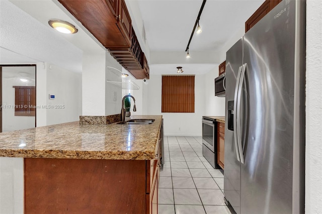 kitchen featuring light stone countertops, kitchen peninsula, stainless steel appliances, sink, and light tile patterned floors