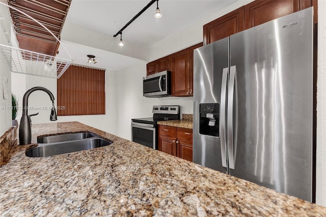 kitchen with light stone countertops, sink, rail lighting, and stainless steel appliances