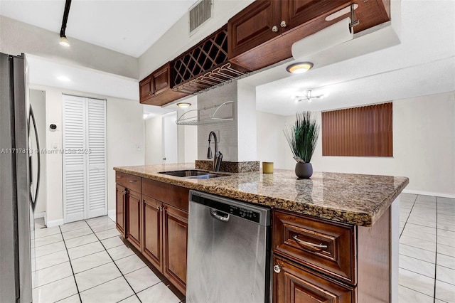 kitchen featuring appliances with stainless steel finishes, light tile patterned floors, dark stone countertops, and sink