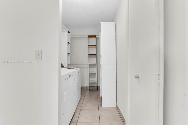 clothes washing area featuring washing machine and dryer, light tile patterned floors, and a textured ceiling