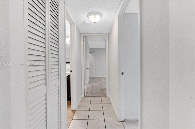 hall featuring light tile patterned floors and a textured ceiling