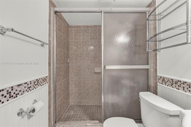 bathroom with radiator heating unit, a shower with shower door, tile walls, and toilet