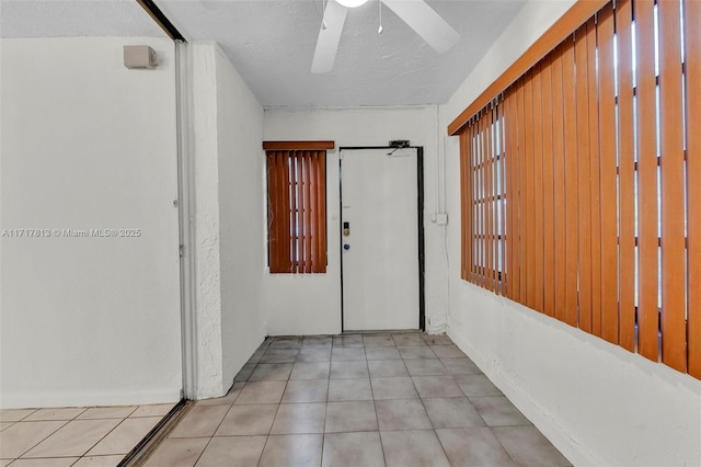 hall featuring light tile patterned floors and a textured ceiling