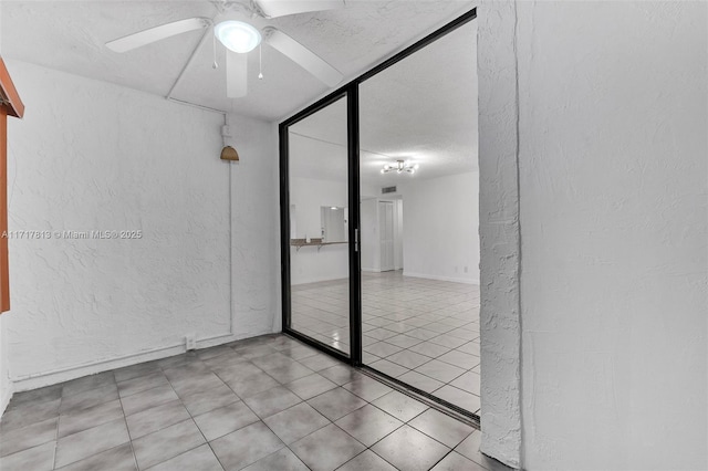 tiled empty room featuring a textured ceiling and ceiling fan