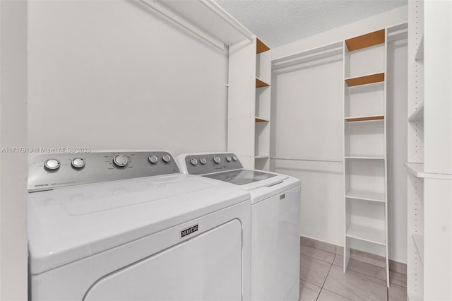 laundry area with independent washer and dryer, a textured ceiling, and light tile patterned floors