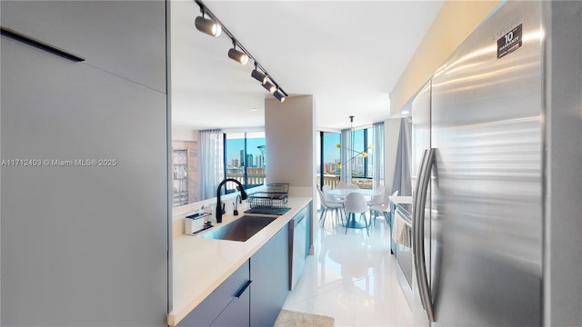 kitchen featuring floor to ceiling windows, sink, hanging light fixtures, light tile patterned floors, and stainless steel appliances