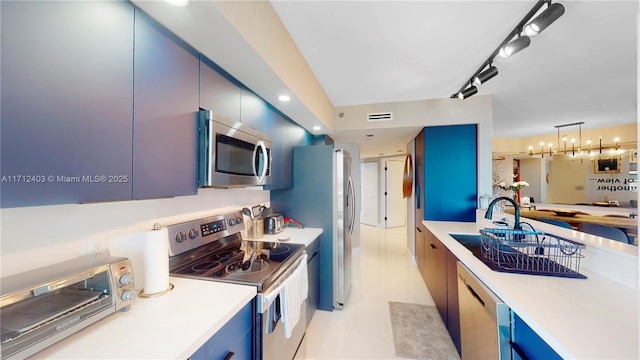 kitchen with blue cabinetry, sink, stainless steel appliances, and decorative light fixtures