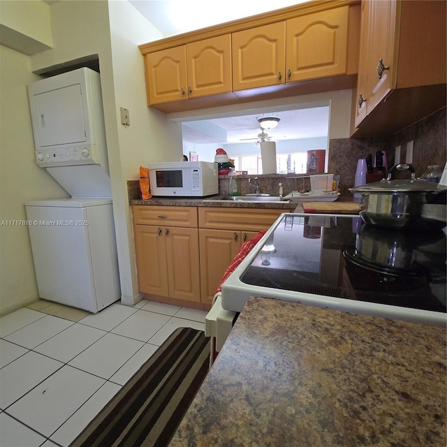 kitchen featuring backsplash, sink, light tile patterned floors, and stacked washer and clothes dryer