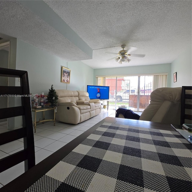 living room with tile patterned flooring, ceiling fan, and a textured ceiling