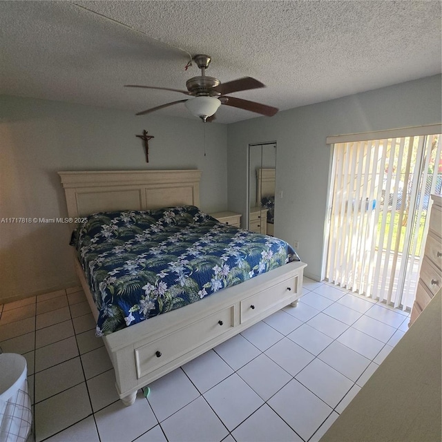 bedroom featuring ceiling fan, light tile patterned flooring, and a textured ceiling