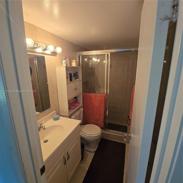 bathroom featuring tile patterned flooring, vanity, toilet, and an enclosed shower